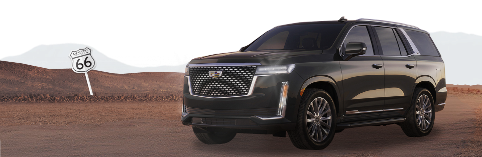 Ciemny Cadillac Escalade na pustynnej drodze obok znaku Route 66
