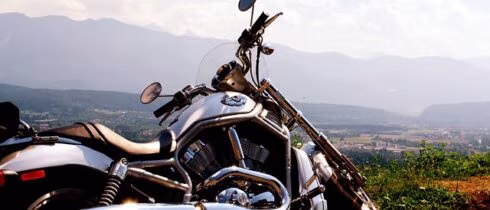 Chromowany motocykl zaparkowany na wzgórzu z widokiem na dolinę i góry