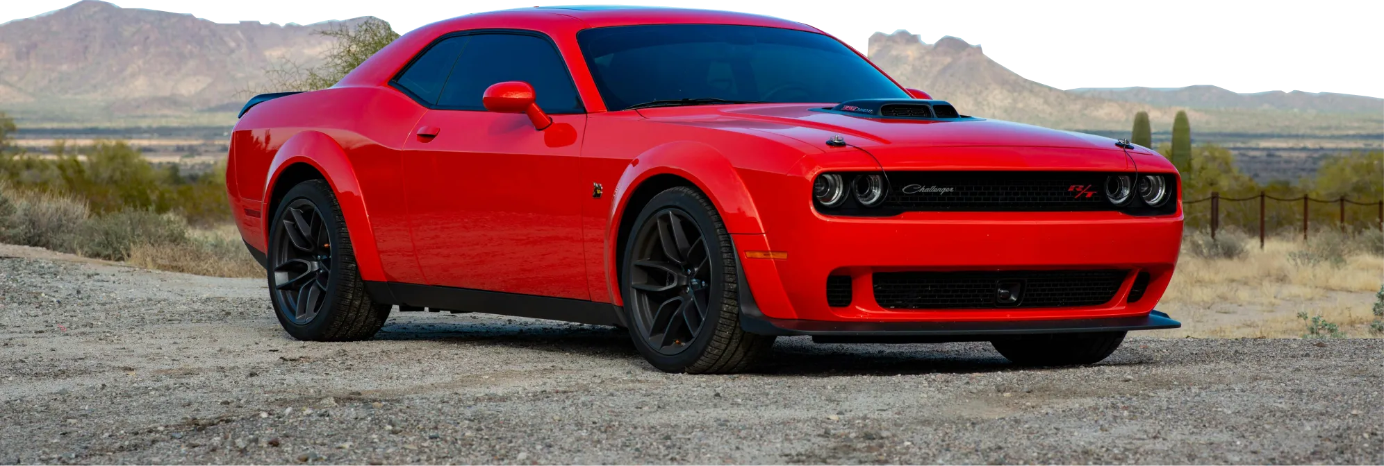 Czerwony Dodge Challenger Widebody na pustynnej drodze z górami w tle
