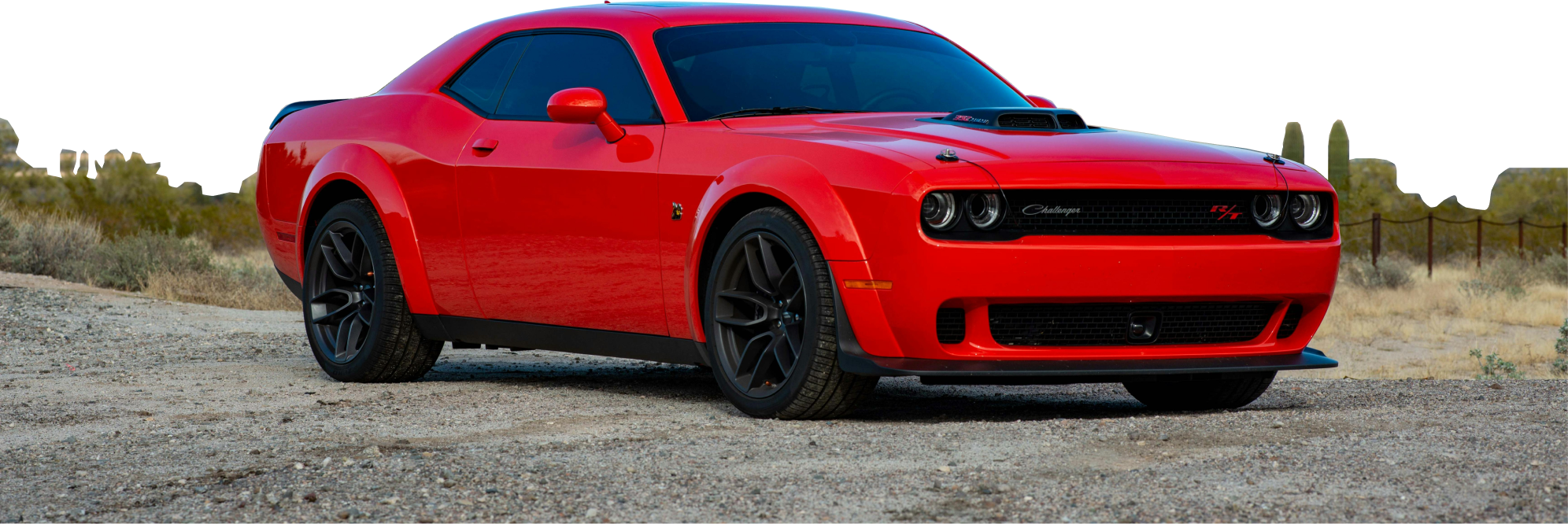 Czerwony Dodge Challenger stoi na żwirowej drodze w pustynnym krajobrazie