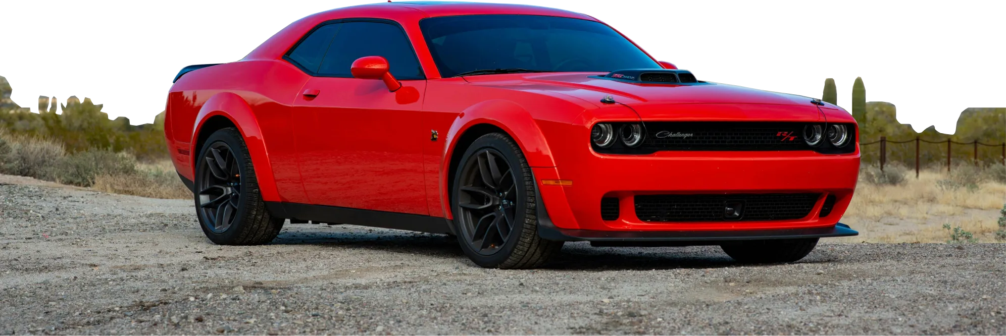 Czerwony Dodge Challenger stoi na żwirowej drodze w pustynnym krajobrazie