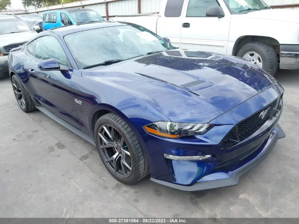 Niebieski Ford Mustang GT 5.0 zaparkowany na placu aukcyjnym, widok z przodu i boku