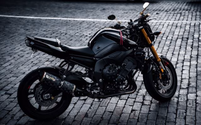 Czarny motocykl sportowy zaparkowany na brukowanej ulicy w miejskiej scenerii