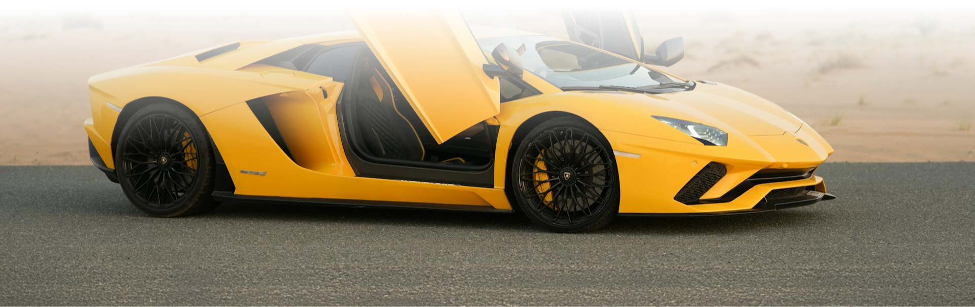 Żółte Lamborghini Aventador z uniesionymi drzwiami stoi na pustynnej drodze