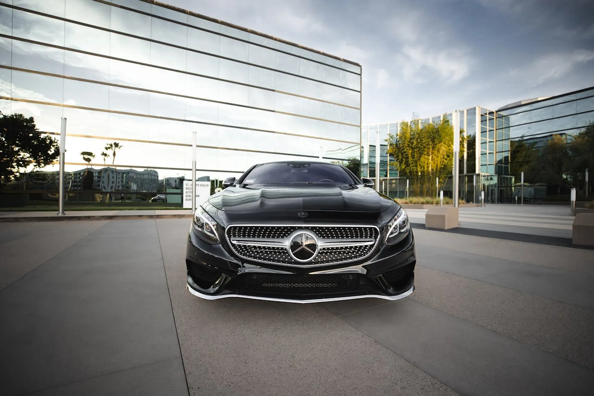 Czarny Mercedes zaparkowany przed nowoczesnym szklanym budynkiem