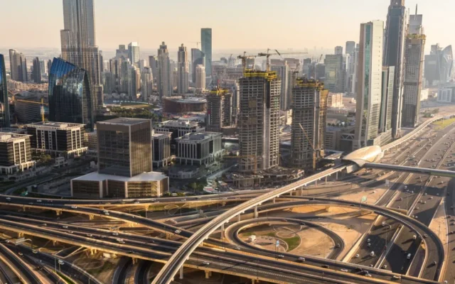 Panorama Dubaju z wieżowcami, węzłem autostrad i ruchem na Sheikh Zayed Road o zachodzie słońca
