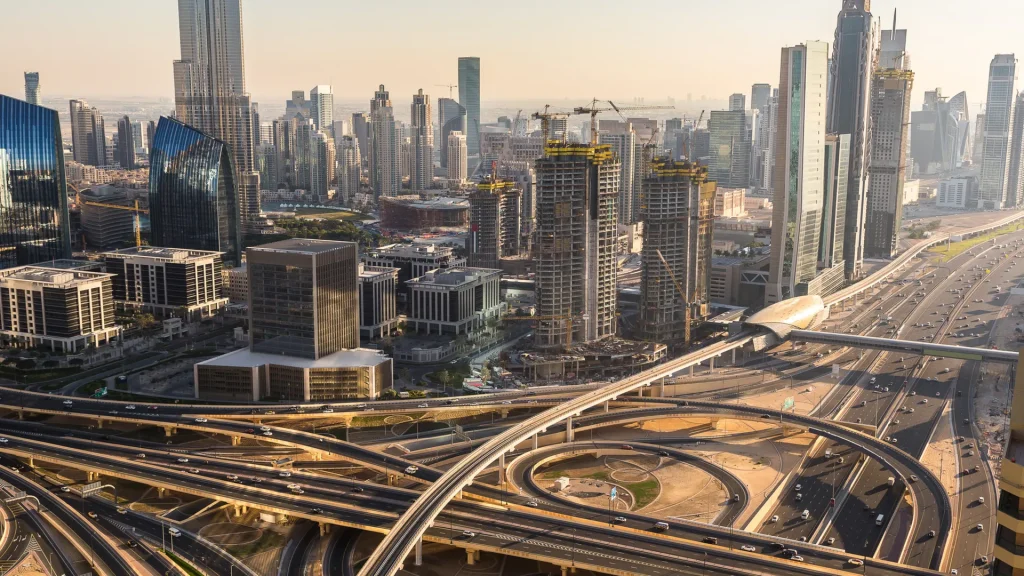 Panorama Dubaju z wieżowcami, węzłem autostrad i ruchem na Sheikh Zayed Road o zachodzie słońca