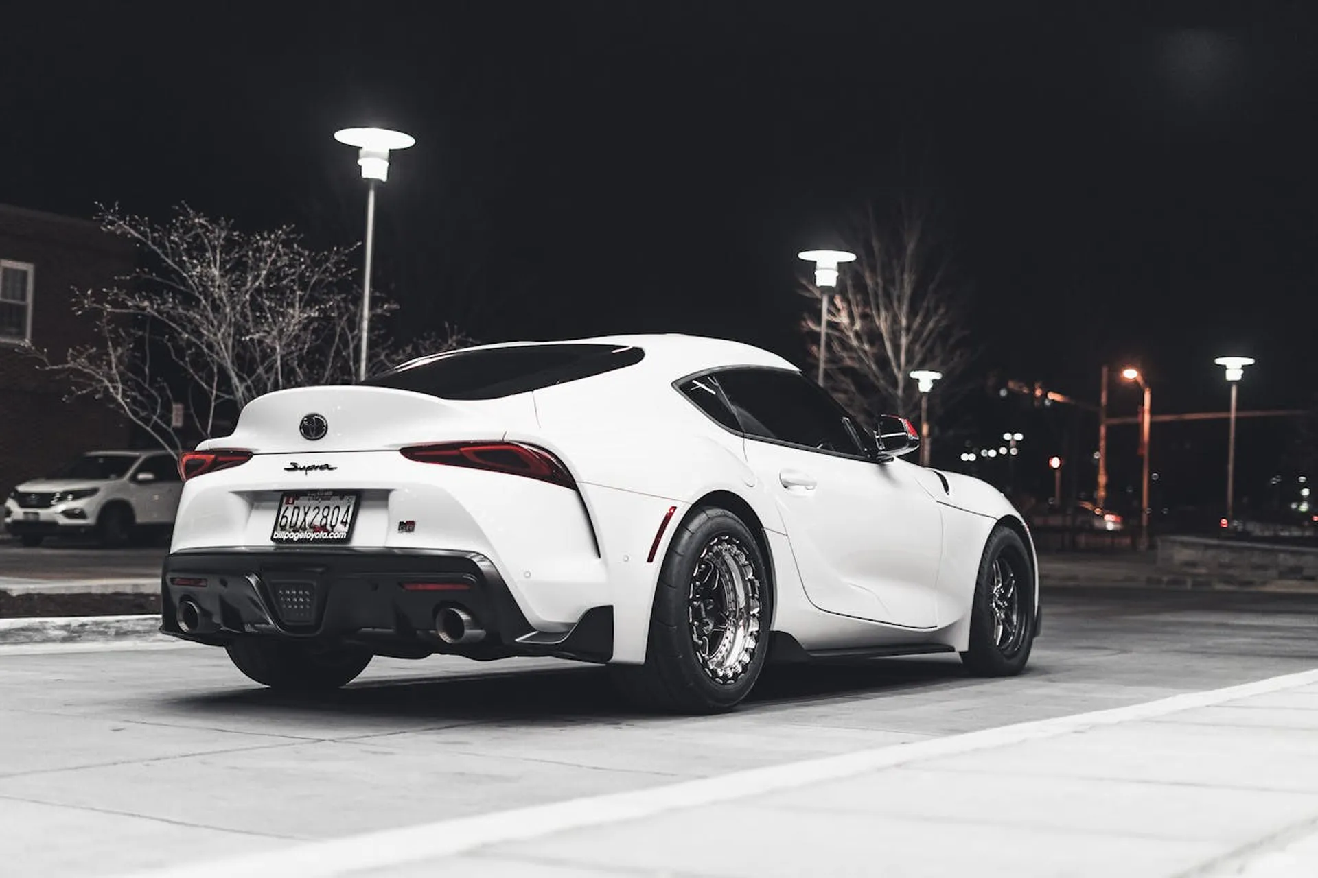 Biała Toyota Supra zaparkowana nocą na oświetlonym parkingu