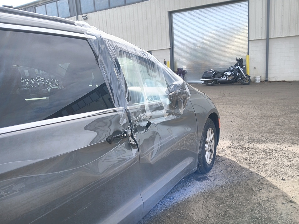 Bok szarego Chryslera Pacifica z folią na szybie, zdjęcie zrobione przy hali serwisowej