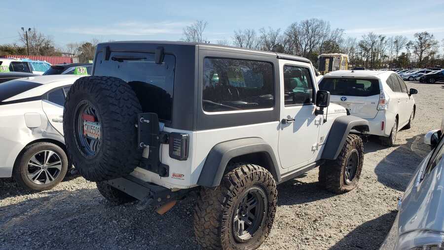 Biały Jeep Wrangler Rubicon, widok od tyłu z boku na placu