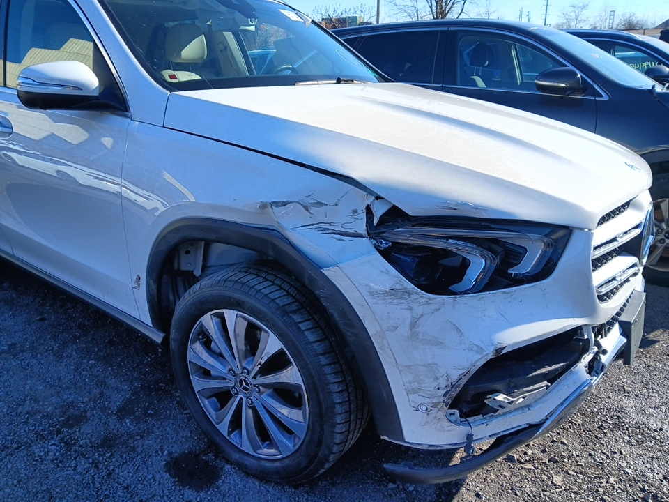 Uszkodzony przedni zderzak i błotnik białego Mercedesa-Benz GLE