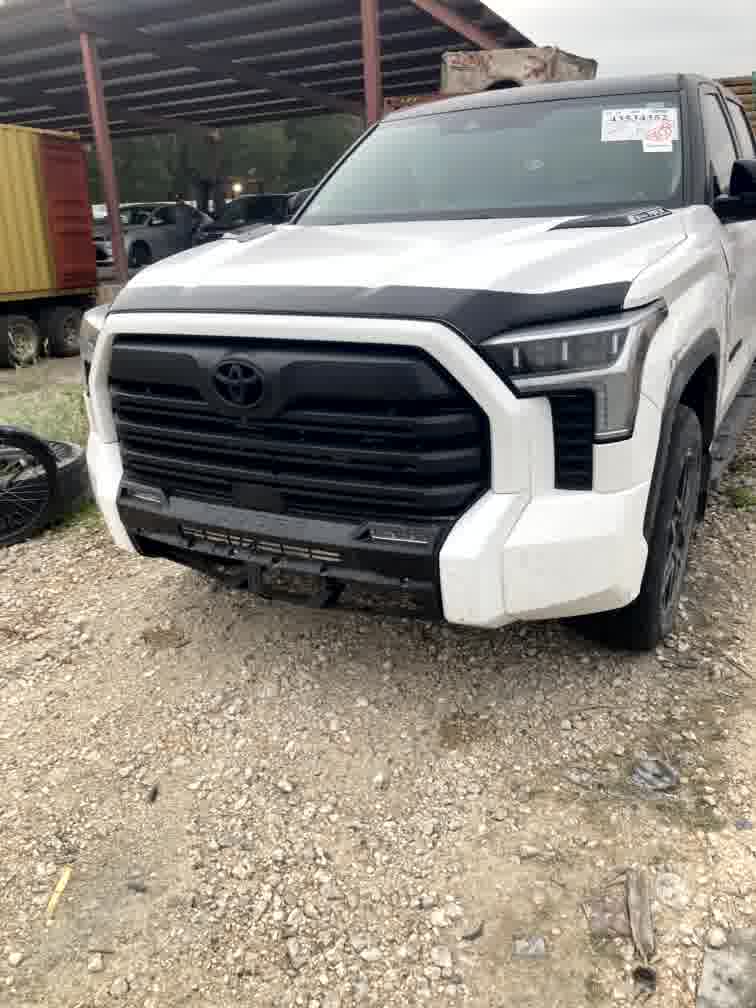 Biała Toyota Tundra widziana od przodu, na placu z autami z USA